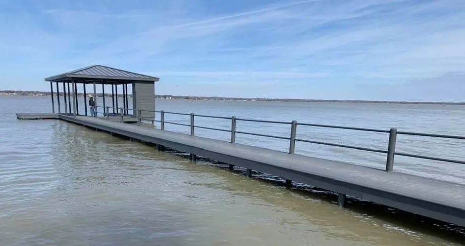 download (9) A long deck leading to a dock where a man is standing under a covered roof