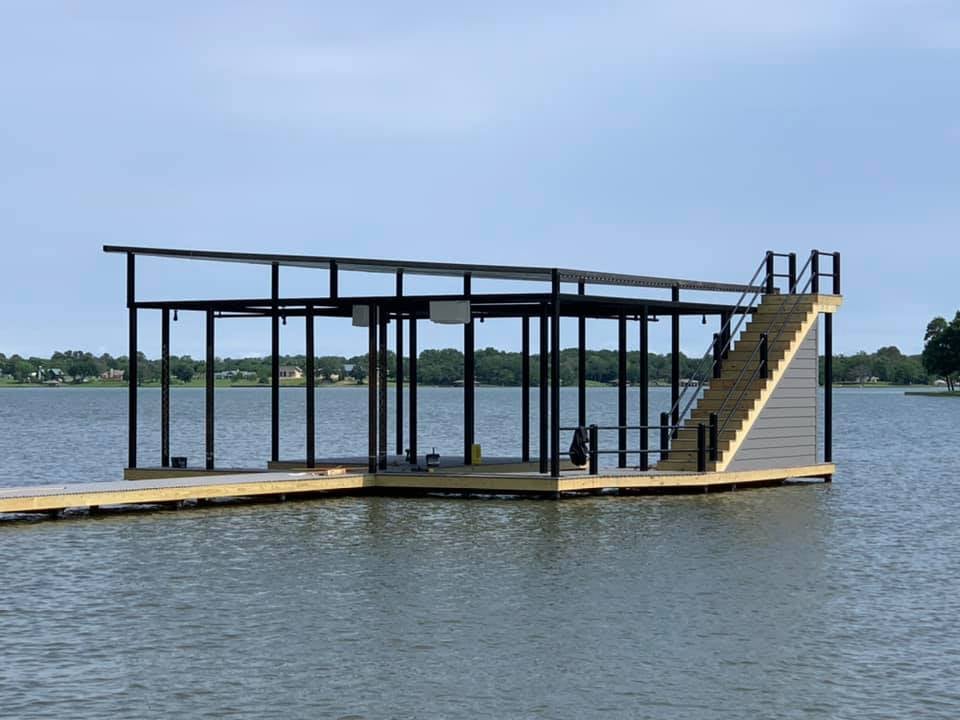 274877470_467735368216925_7436479084795120686_n A view from the water of a custom boat ramp and covered deck pictured with stairs