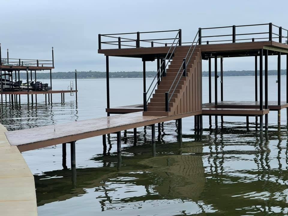 275013048_467714234885705_8482443909460824343_n A brown dock on the water pictured with stairs and darker accents