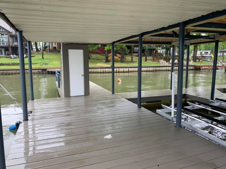 275097033_467756454881483_8235411504967633461_n View from a double boat holding boat house deck facing the land with a white door behind the stairs in view